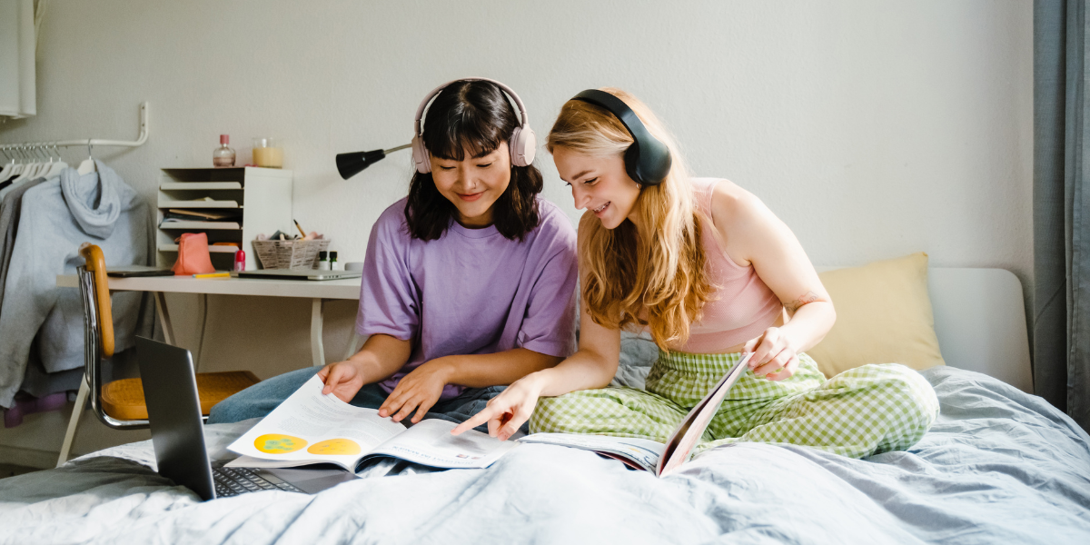 Two teenagers in their bedroom, happily completing homework assignments. The setting illustrates the importance of having a dedicated and distraction-free study space for teens to stay focused.