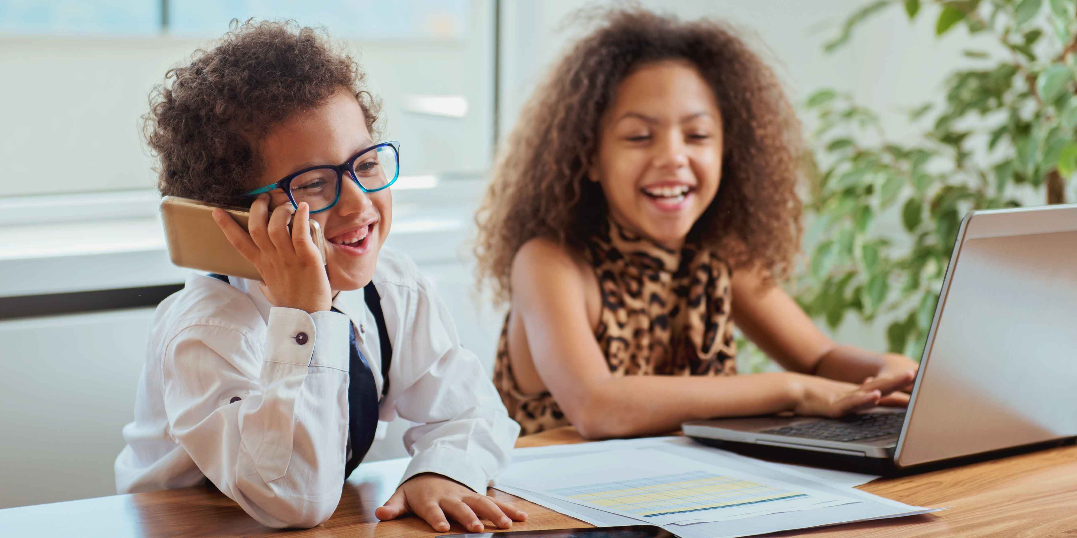 Two children role-playing as entrepreneurs, working together at a mock lemonade stand with playful props, showcasing teamwork and business skills.