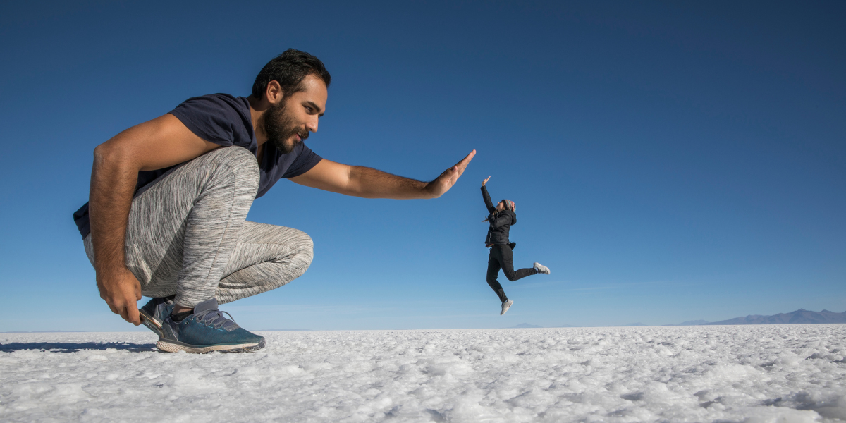 An optical illusion demonstrating perspective, where a person close to the camera appears like a giant compared to a distant person.